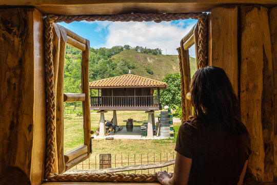 Woman admiring asturian landscape from wooden cabin window in benia de onis