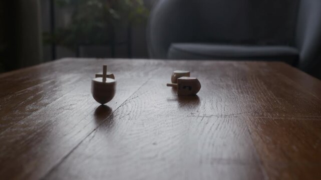 Cropped close up shot of hands of unrecognizable person spinning dreidel on table during Hanukkah celebration