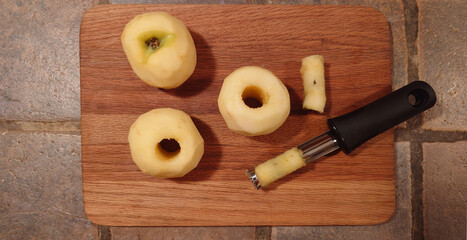 wooden cutting board with cored apples and apple corer