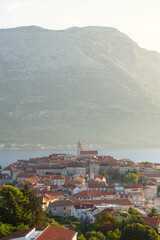Fototapeta premium Die Altstadt von Korčula vor dem Gebirgsmasssiv des Sv. Ilija auf der Halbinsel Pelješac im Gegenlicht der Morgensonne, Insel Korčula, Süddalmatien, Kroatien