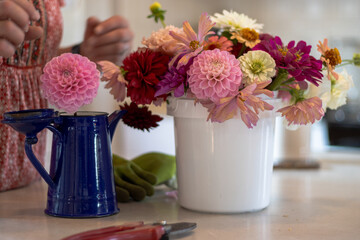 Indoor bouquet and enamel pitcher with hands arranging