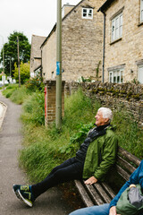 Older man sits on a bus stop bench in ancient stone village