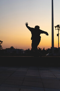 Man performing a trick on roller skates at sunset, urban environment