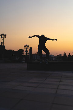 Man performing a trick on roller skates at sunset, urban environment