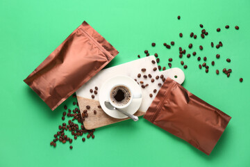Brown bags with coffee beans and cup of hot espresso on green background