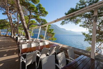Leere Tische und Stühle auf den Terassen der Restaurants an der Satdtmauer der Altstadt von Korčula in der Morgensonne, Inselk Korčula, Süddalmatien, Kroatien