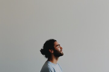 Obraz premium Peaceful Young Man With A Beard And Man Bun Relaxing Against A Minimalist Grey Background