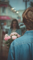 A handsome young man holds flowers behind his back for a beautiful girl. View from behind. A wonderful first date.