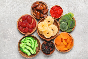 Bowls with different candied fruits on grey background