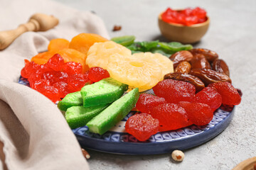 Plate with different candied fruits on grey background, closeup