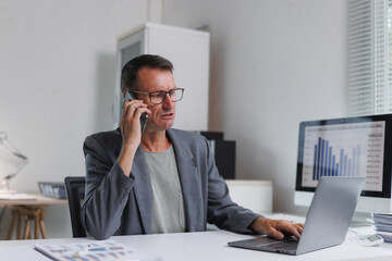 Naklejka premium Mature businessman having phone conversation while working