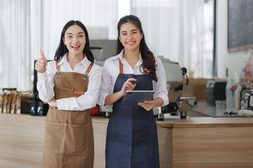 Coffee shop partners smiling and holding tablet, giving thumbs up