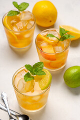 Glasses of fruit tea with lemon slices and mint leaves on white background