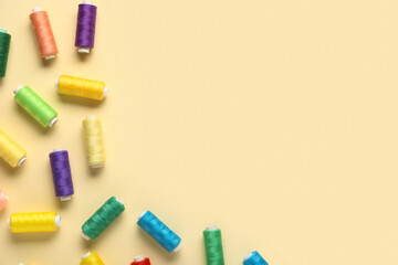 Colorful thread spools on beige background