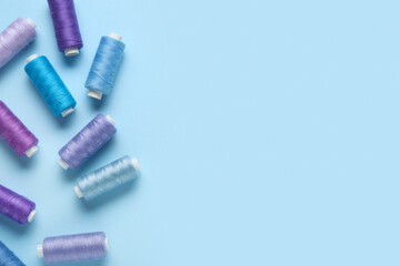 Colorful thread spools on blue background