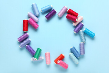Frame made of colorful thread spools on blue background