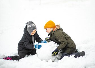 Cute little girl and boy in winter sunny day building snowman outdoor nature winter. Outdoor winter activity. Happy childhood. Christmas and New Year concept.