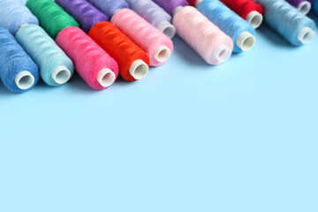 Many colorful thread spools on blue background