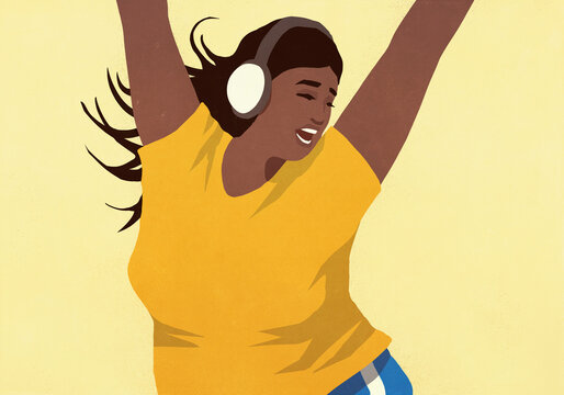 Carefree young woman with headphones listening to music and dancing with arms raised

