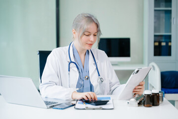 Healthcare costs and fees concept.Hand of smart doctor used a calculator and smartphone, tablet for medical costs at hospital