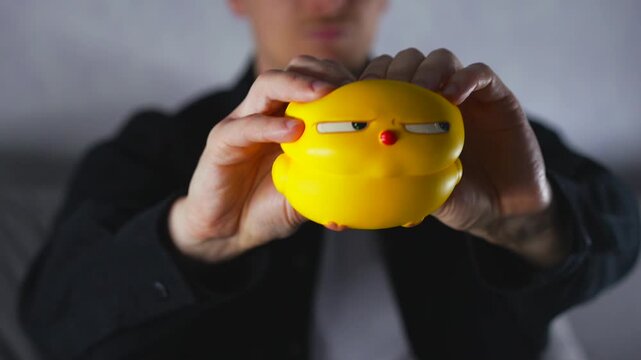 A man holds a yellow anti-stress toy.
A calming yellow toy.
The man kneads the toy with his hands to calm and stabilize his nerves from stress.