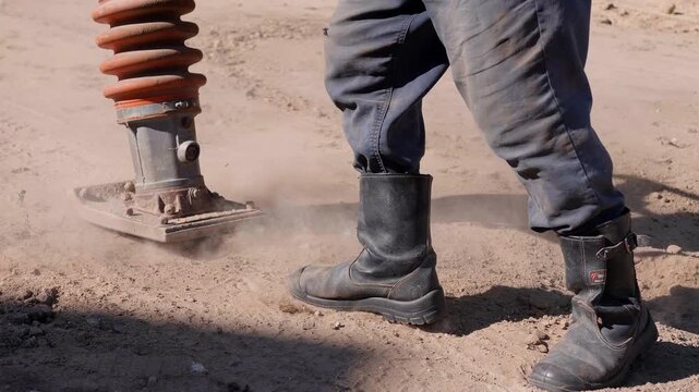 Heavy-duty soil compactor in action, compressing loose dirt for road repair, creating dust clouds and showcasing the dynamic process of ground stabilization