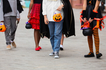 Group of kids dressed for Halloween with candies walking on street