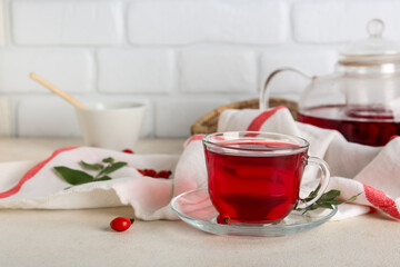 Glass cup of hot rose hip tea on white table
