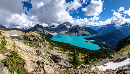 Wide landscape captures a vibrant turquoise lake surrounded by rugged, snow-capped mountains under a bright, blue sky filled with fluffy clouds