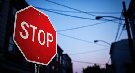 Red stop sign with bold white letters against an urban twilight sky