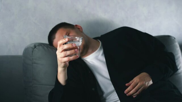 A very drunk man on a sofa with an alcoholic cocktail is talking about something.
Facial expressions of a drunk man.
Alcohol intoxication and regular alcohol consumption