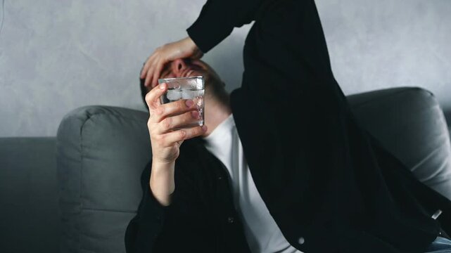 A very drunk man on a sofa with an alcoholic cocktail is talking about something.
Facial expressions of a drunk man.
Alcohol intoxication and regular alcohol consumption
