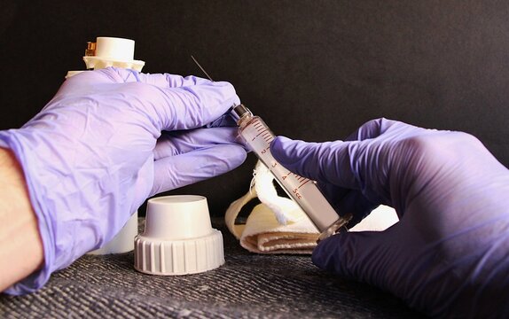 Jeringa de hospital en manos de enfermero m&eacute;dico practicante con guantes de l&aacute;tex azules