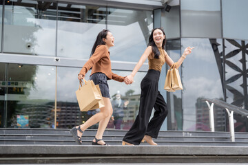 Two happy asian women shopping at modern mall