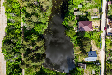 A bird's-eye perspective of a compact lake nestled amidst vacation homes