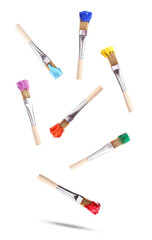 dynamic photograph showcasing eight wooden paint brushes tipped with bright, vibrant colors of acrylic paint, scattered and floating against a clean transparent background.