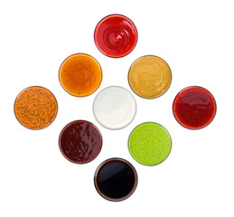 aerial photograph of nine small dipping bowls containing various colorful sauces and condiments, including ketchup, soy sauce, and mayonnaise, isolated on black.
