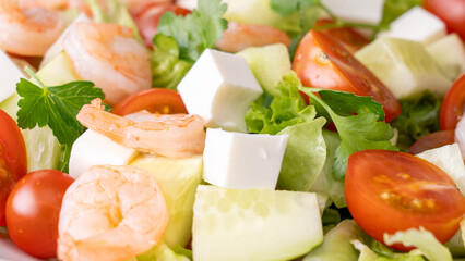 A salad with shrimp, tomatoes, cucumbers, and lettuce. The salad is colorful and fresh