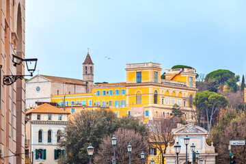 View of the Real Academia de Espana en Roma and the Church of San Pietro in Montorio on the Janiculum Hill in Rome. The yellow building and white church stand out against a hazy sky Rome