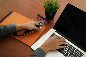 Doctor Working on Laptop with Stethoscope on Desk