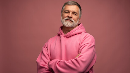 Obraz premium Caucasian smiling bearded mature man wearing pink hoodie against pink background