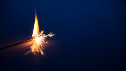 Close up of a sparkler burning against a dark blue background