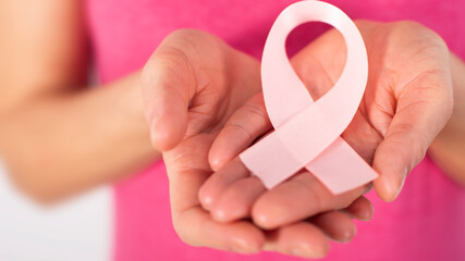 Caucasian female middle aged model shows breast cancer awareness pink ribbon closeup view