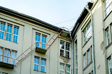 Metal fire escape ladder attached to exterior wall of aged multi-story building.