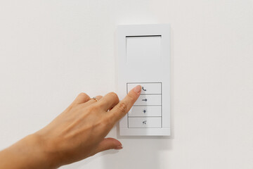 Hand pressing button on smart wall control panel. Modern home automation system for light, lock,...