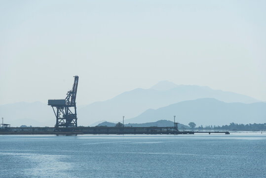Verladekran an einem Verladepier im Hafen von Ploče vor Bergen im Dunst im Gegenlicht der Morgensonne, Dalmatien, Kroatien