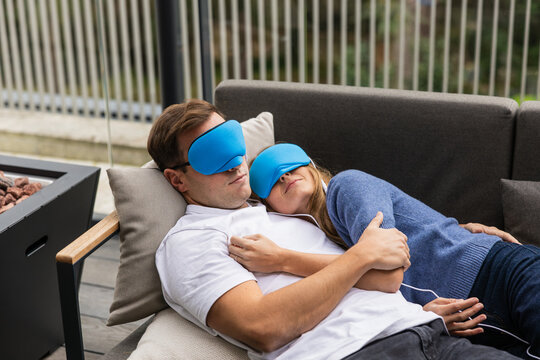 Couple relaxing on sofa with sleep masks and temperature controller