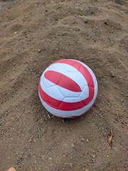 Red and White Striped Ball on Sandy Ground
