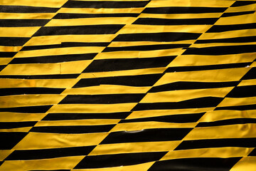 Yellow and black wobbly and slanted grid created from old barricade tape