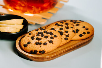 Warm tea and chocolate chip cookies on a cozy table with lemon slices